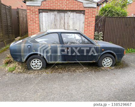 A rusted vintage car being abandoned on a street with flat tires and rusty bodywork 138529667