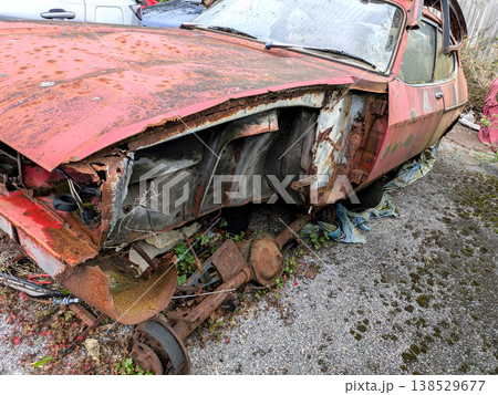 A rusted vintage car being abandoned on a street with flat tires and rusty bodywork 138529677