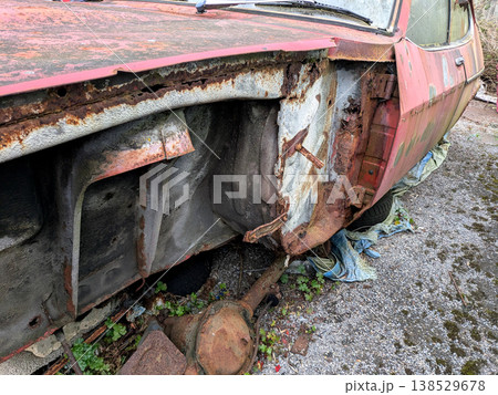 A rusted vintage car being abandoned on a street with flat tires and rusty bodywork 138529678