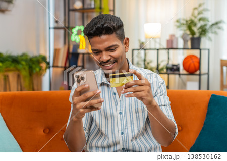 Indian man shops online with smartphone and card enters cvv confirms order success smiles delivery Indian man shops online with smartphone and card enters cvv confirms order success smiles delivery 138530162