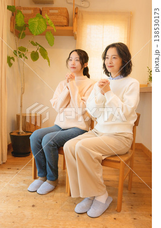 自宅で故人に祈りを捧げる母と娘 138530173