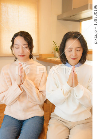 自宅で故人に祈りを捧げる母と娘 自宅で故人に祈りを捧げる母と娘 138530196
