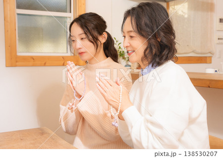 自宅で故人に祈りを捧げる母と娘 自宅で故人に祈りを捧げる母と娘 138530207