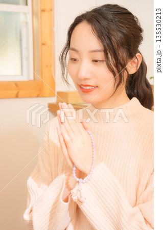 自宅で故人に祈りを捧げる娘 138530213