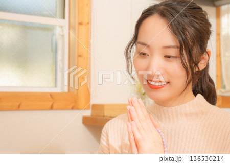 自宅で故人に祈りを捧げる娘 自宅で故人に祈りを捧げる娘 138530214