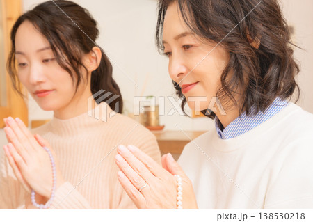 自宅で故人に祈りを捧げる母と娘 138530218