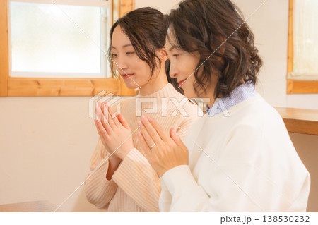 自宅で故人に祈りを捧げる母と娘 138530232