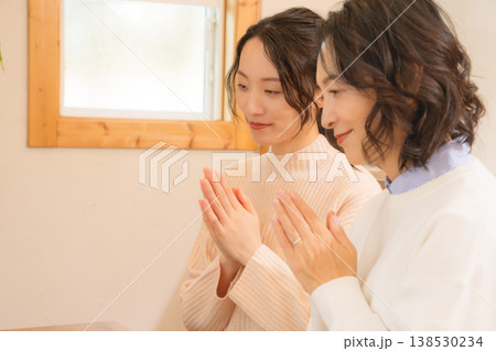 自宅で故人に祈りを捧げる母と娘 自宅で故人に祈りを捧げる母と娘 138530234