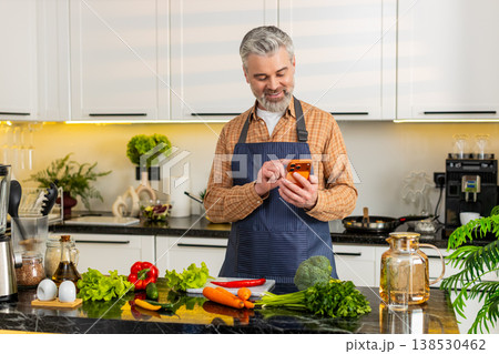 Middle-aged man choosing healthy groceries using smartphone in home kitchen for diet meal planning Middle-aged man choosing healthy groceries using smartphone in home kitchen for diet meal planning 138530462