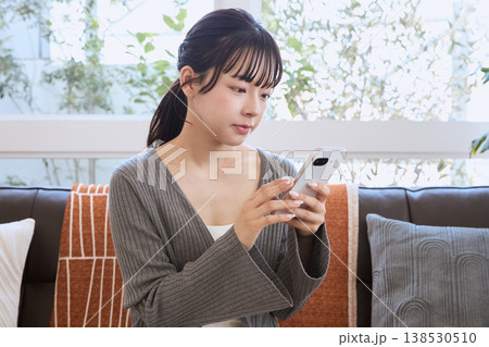 リビングでスマートフォンを見る女性 リビングでくつろぐライフスタイル リビングでスマートフォンを見る女性 リビングでくつろぐライフスタイル 138530510