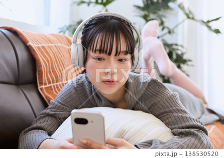 ヘッドホンでスマートフォンを楽しむ女性　リビングでくつろぐライフスタイル 138530520