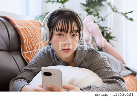 ヘッドホンでスマートフォンを楽しむ女性　リビングでくつろぐライフスタイル 138530521
