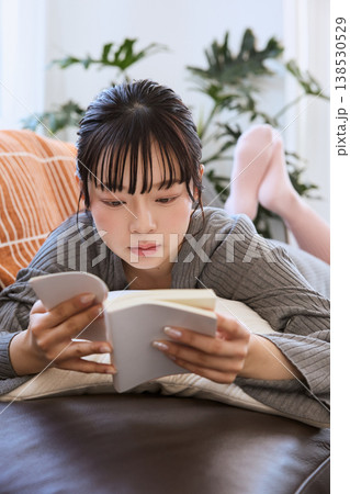 ソファで寝転び本を読む女性　自宅でくつろぐ読書の時間 138530529