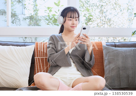 ヘッドホンでスマートフォンを使う女性 自宅で楽しむライフスタイル ヘッドホンでスマートフォンを使う女性 自宅で楽しむライフスタイル 138530539