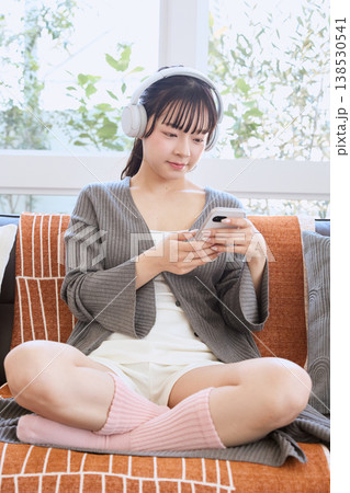 ヘッドホンでスマートフォンを使う女性 自宅で楽しむライフスタイル ヘッドホンでスマートフォンを使う女性 自宅で楽しむライフスタイル 138530541