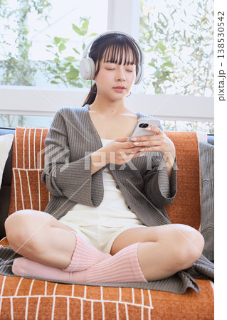 ヘッドホンでスマートフォンを使う女性 自宅で楽しむライフスタイル ヘッドホンでスマートフォンを使う女性 自宅で楽しむライフスタイル 138530542
