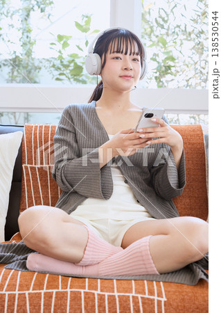 ヘッドホンでスマートフォンを使う女性 自宅で楽しむライフスタイル ヘッドホンでスマートフォンを使う女性 自宅で楽しむライフスタイル 138530544