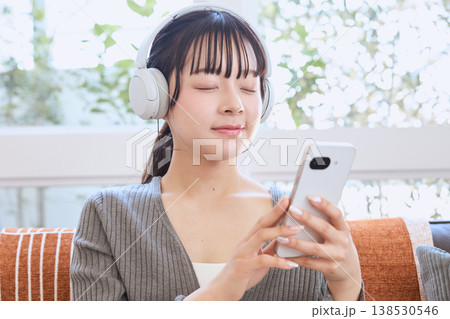 ヘッドホンでスマートフォンを使う女性　自宅で楽しむライフスタイル 138530546