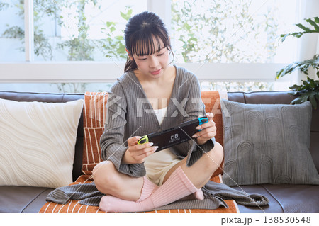 携帯ゲーム機で遊ぶ女性　自宅でくつろぐ休日 138530548