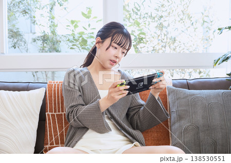 携帯ゲーム機で遊ぶ女性　自宅でくつろぐ休日 138530551