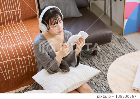 ヘッドホンをつけて本を読みながら考える若い女性 ヘッドホンをつけて本を読みながら考える若い女性 138530567
