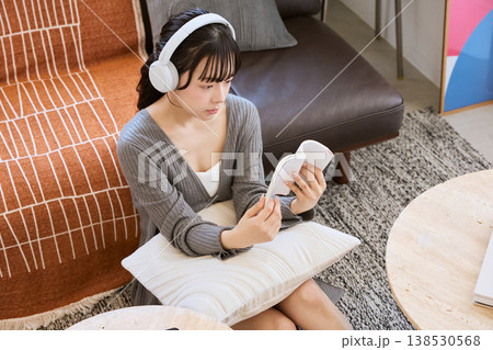 ヘッドホンをつけて本を読みながら考える若い女性 138530568