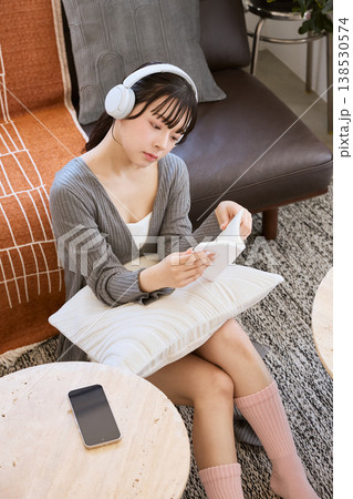 ヘッドホンをつけて本を読みながら考える若い女性 138530574