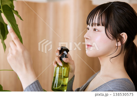 観葉植物に霧吹きで水を与える若い女性 138530575