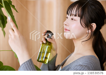 観葉植物に霧吹きで水を与える若い女性 138530576