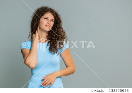 Woman rubbing painful neck suffering discomfort muscle tension stress tired exhausted expression Woman rubbing painful neck suffering discomfort muscle tension stress tired exhausted expression 138530638