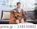 自宅のリビングでアコースティックギターを持つ若い女性 138530802