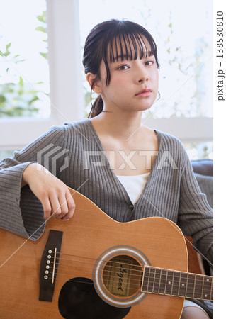 自宅のリビングでアコースティックギターを持つ若い女性 自宅のリビングでアコースティックギターを持つ若い女性 138530810