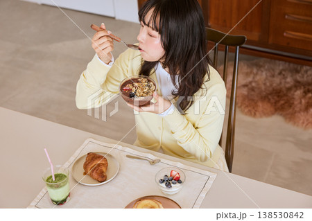 アサイーボウルを食べる若い女性の健康的な朝食シーン 138530842