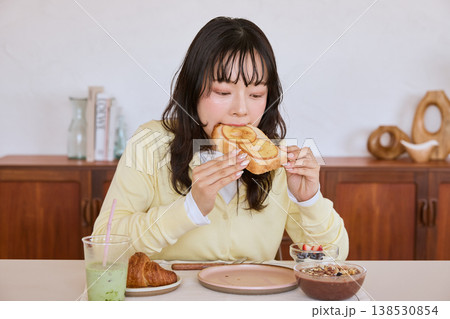 自宅で朝食のトーストを食べる若い女性 138530854