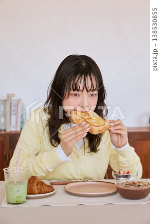 自宅で朝食のトーストを食べる若い女性 138530855