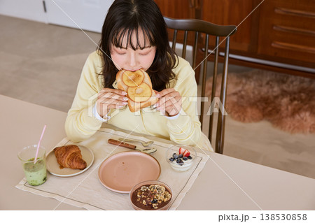 自宅で朝食のトーストを食べる若い女性 138530858