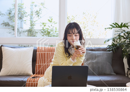 自宅でビールを楽しみながら動画を見る女性 自宅でビールを楽しみながら動画を見る女性 138530864