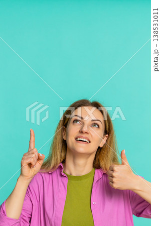 Woman pointing up with serious expression drawing attention to important thing or key information Woman pointing up with serious expression drawing attention to important thing or key information 138531011