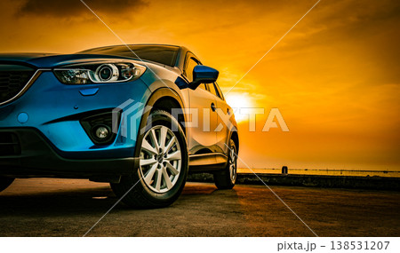 Blue compact SUV car with sport and modern design parked on concrete road by sea beach at sunset. New shiny SUV car drive for travel on summer vacations with road trip. Front view of electric car. 138531207