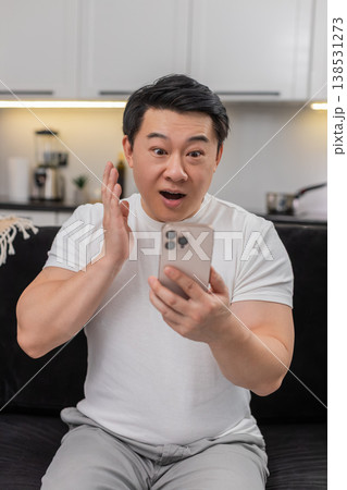 Asian man reads good news on smartphone eyes wide says wow smiles and shares positive update in chat Asian man reads good news on smartphone eyes wide says wow smiles and shares positive update in chat 138531273