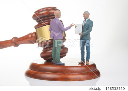 Miniature people engage in discussion near a gavel in a legal setting during daytime Miniature people engage in discussion near a gavel in a legal setting during daytime 138532360