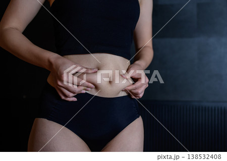 少し太ったお腹の贅肉をつまむ若い女性 太り始め 少し太ったお腹の贅肉をつまむ若い女性 太り始め 138532408