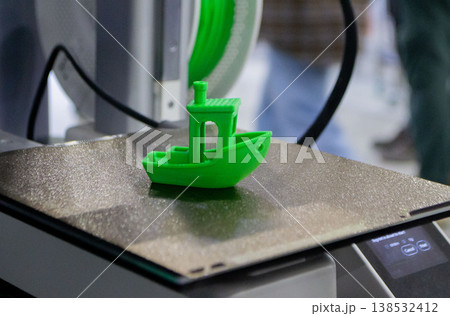 3D printed art object. Object printed on 3D printer from melted colored plastic. Model in shape little green boat created on 3D printer from threads of molten plastic on working surface of 3D printer 138532412