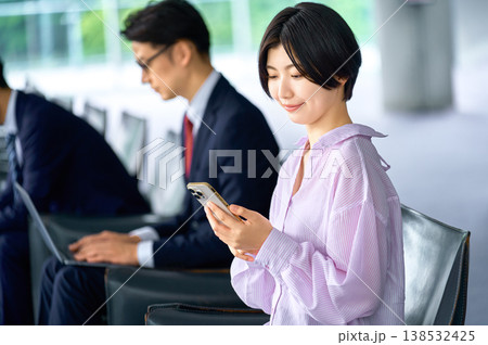 オフィスラウンジでスマートフォンを操作する女性と働くビジネスマン 138532425