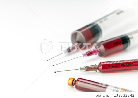 Close-Up of Several Blood-Filled Single Use Only Medical Syringes With Sharp Exposed Needles Arranged on a Clean White Background for Healthcare Concepts 138532542