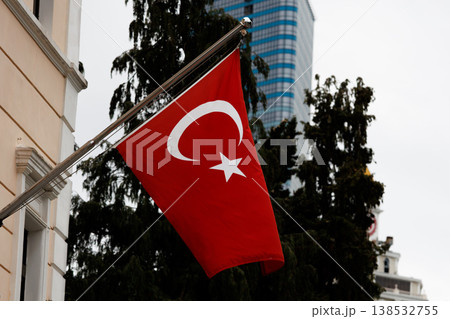Red flag with white crescent and star on building facade, national symbol waving in urban environment, patriotic concept with modern city background and architectural elements Red flag with white crescent and star on building facade, national symbol waving in urban environment, patriotic concept with modern city background and architectural elements 138532755