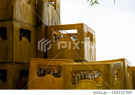 Stacked yellow plastic crates with glass bottles, industrial storage and beverage distribution concept, reusable containers for logistics and recycling, warehouse supply background 138532760