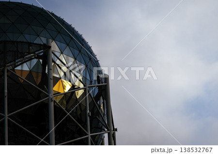 Modern glass dome architecture with geometric triangular panels and steel structure, futuristic building exterior reflecting warm sunset light, abstract urban design, minimal composition with copy spa Modern glass dome architecture with geometric triangular panels and steel structure, futuristic building exterior reflecting warm sunset light, abstract urban design, minimal composition with copy spa 138532767