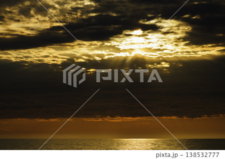 Golden sunset over calm sea with dramatic clouds and sun rays breaking through sky, warm orange horizon, tranquil ocean surface, atmospheric seascape, natural light, serene evening landscape Golden sunset over calm sea with dramatic clouds and sun rays breaking through sky, warm orange horizon, tranquil ocean surface, atmospheric seascape, natural light, serene evening landscape 138532777