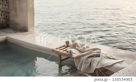 minimalist wooden chaise lounge draped in linen, set on the edge of an ancient greek pool overlooking the sea, with two cups of coffee beside it. minimalist wooden chaise lounge draped in linen, set on the edge of an ancient greek pool overlooking the sea, with two cups of coffee beside it. 138534903